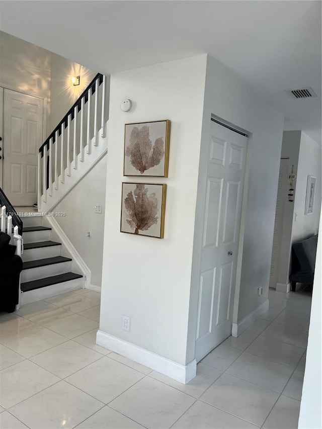 stairs featuring baseboards, tile patterned floors, and visible vents