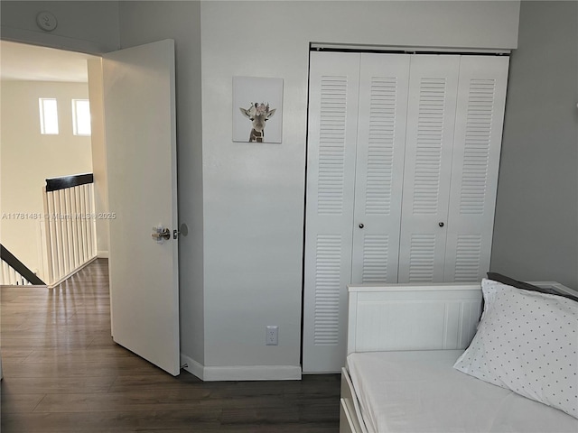 unfurnished bedroom with baseboards, dark wood-type flooring, and a closet