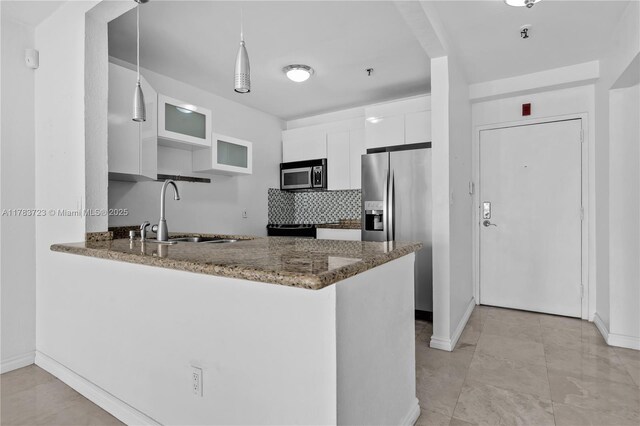 677 NE 24th St Unit 504, Miami, FL 33137 - kitchen with appliances with stainless steel finishes, a peninsula, white cabinets, dark stone countertops, and hanging light fixtures