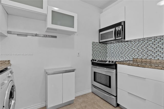 677 NE 24th St Unit 504, Miami, FL 33137 - kitchen with stainless steel appliances, washer / dryer, dark stone countertops, and white cabinetry