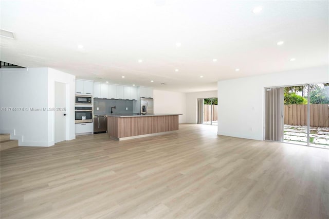 13912 SW 103rd Ln, Miami, FL 33186 - unfurnished living room featuring recessed lighting, stairway, light wood-type flooring, and a healthy amount of sunlight