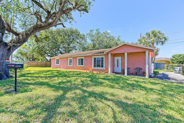 ranch-style home with stucco siding, fence, and a front yard