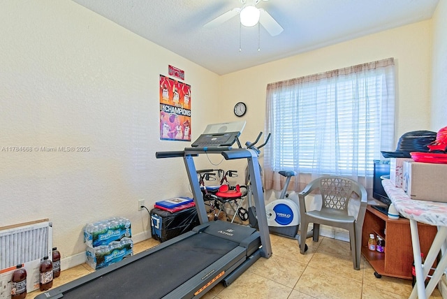 exercise area with ceiling fan and light tile patterned floors