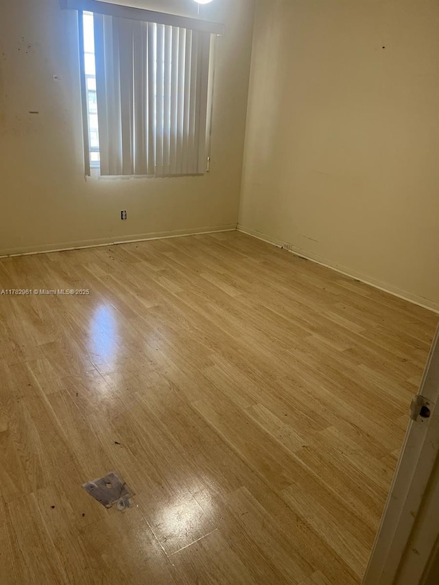 unfurnished room featuring baseboards and light wood-style floors