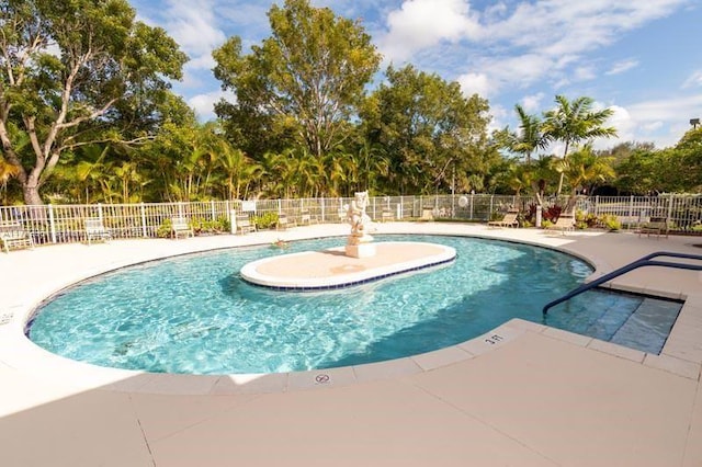 community pool with a patio area and fence