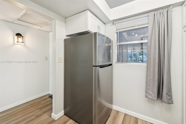 101 Royal Park Dr Unit 1D, Oakland Park, FL 33309 - kitchen featuring light wood-style floors, freestanding refrigerator, visible vents, white cabinets, and baseboards