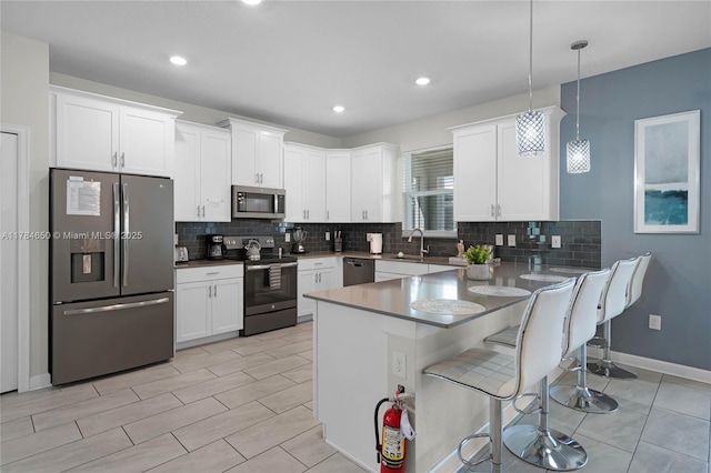 690 Drop, Shot, FL 33896 - kitchen featuring a kitchen bar, a peninsula, white cabinets, appliances with stainless steel finishes, and backsplash
