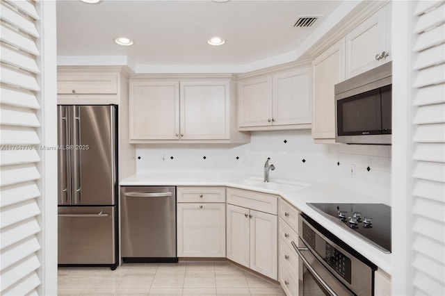 kitchen with visible vents, appliances with stainless steel finishes, light countertops, a sink, and decorative backsplash