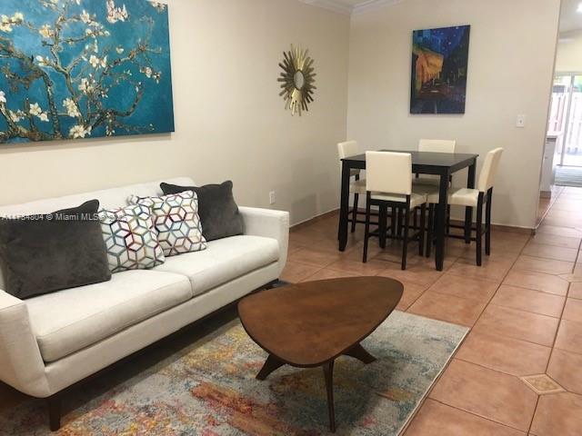 living room with crown molding, tile patterned floors, and baseboards