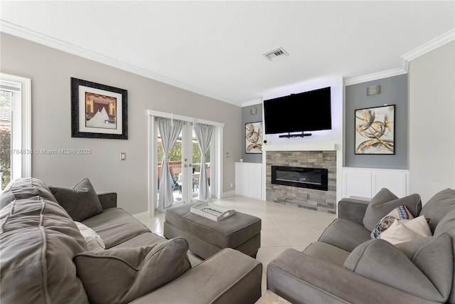living area with a glass covered fireplace, ornamental molding, light tile patterned floors, french doors, and visible vents
