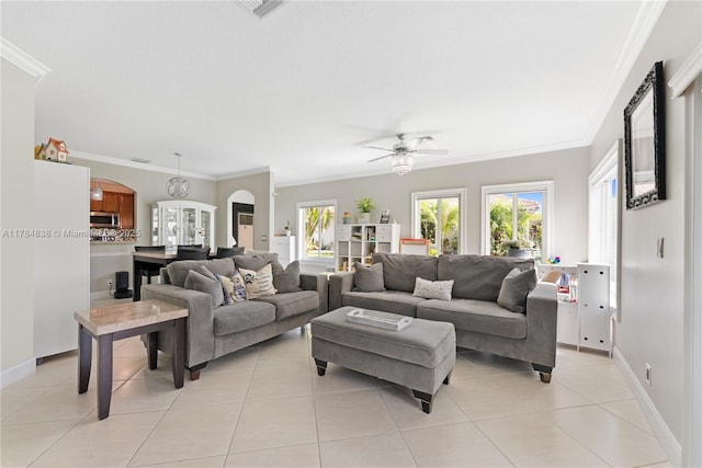 living area with baseboards, arched walkways, a ceiling fan, crown molding, and light tile patterned flooring