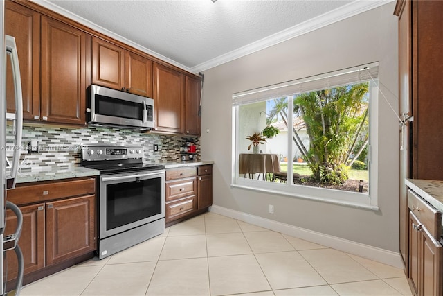 kitchen with light stone countertops, ornamental molding, appliances with stainless steel finishes, baseboards, and backsplash