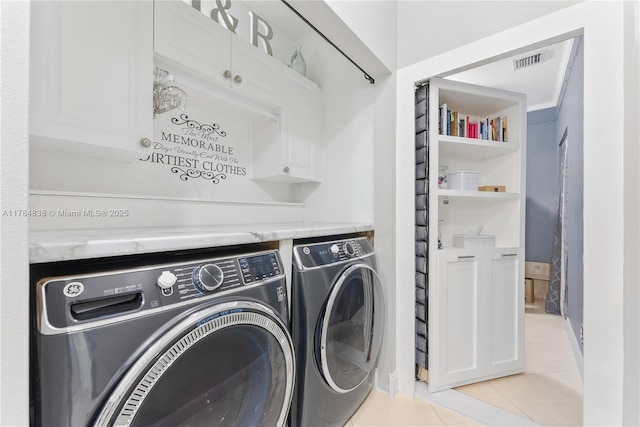 laundry room featuring light tile patterned floors, visible vents, washing machine and clothes dryer, baseboards, and cabinet space