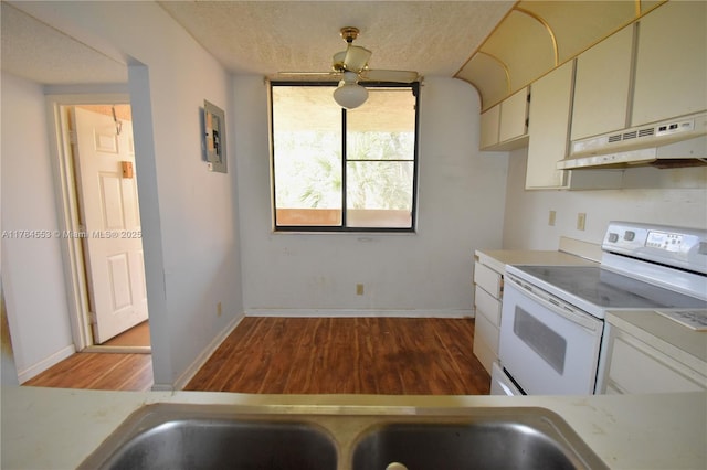 kitchen featuring baseboards, light countertops, under cabinet range hood, white range with electric cooktop, and wood finished floors