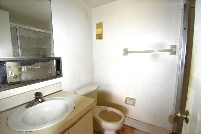 bathroom with a shower with door, vanity, and toilet