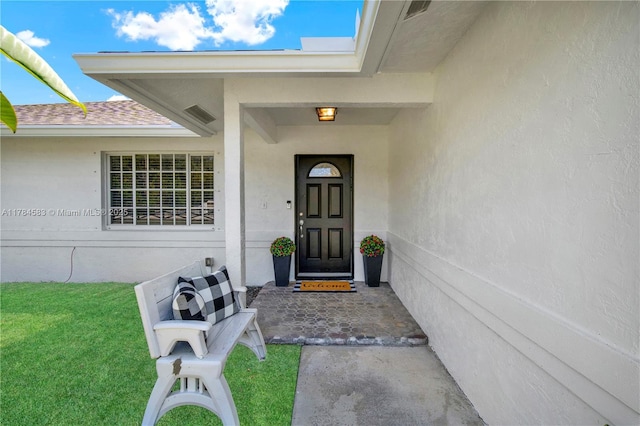 17746 48th Ct N, Loxahatchee, FL 33470 - view of exterior entry with a lawn, a shingled roof, and stucco siding