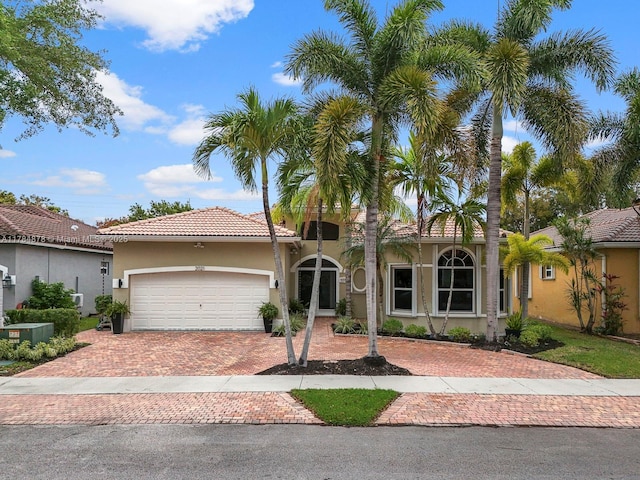 2021 SE 17th Ave, Homestead, FL 33035 - mediterranean / spanish-style house featuring stucco siding, decorative driveway, a garage, and a tile roof