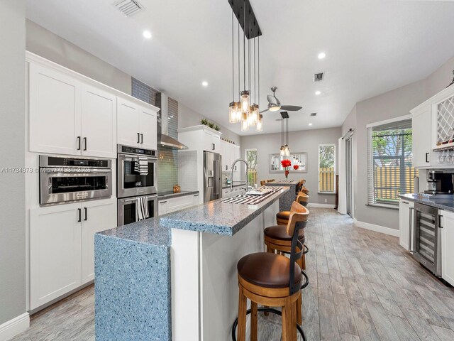 2021 SE 17th Ave, Homestead, FL 33035 - kitchen with stainless steel appliances, beverage cooler, baseboards, light wood finished floors, and a kitchen island with sink