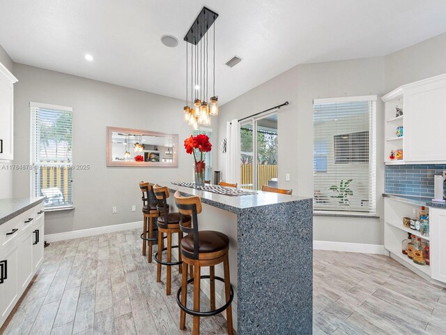 2021 SE 17th Ave, Homestead, FL 33035 - kitchen with open shelves, light wood finished floors, a kitchen bar, white cabinets, and pendant lighting