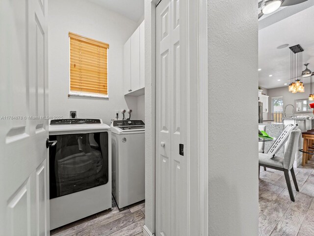2021 SE 17th Ave, Homestead, FL 33035 - washroom with cabinet space, washer and dryer, light wood-type flooring, and a textured wall