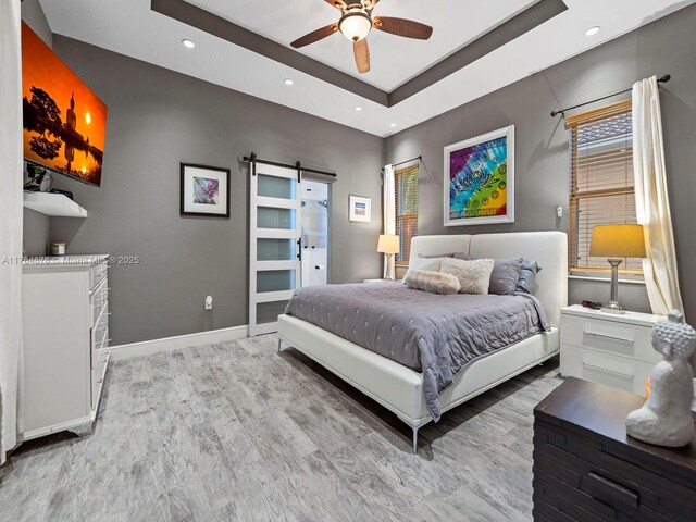 2021 SE 17th Ave, Homestead, FL 33035 - bedroom with a barn door, light wood finished floors, a tray ceiling, baseboards, and recessed lighting