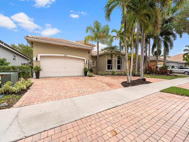 2021 SE 17th Ave, Homestead, FL 33035 - mediterranean / spanish home featuring decorative driveway, stucco siding, a garage, and a tiled roof