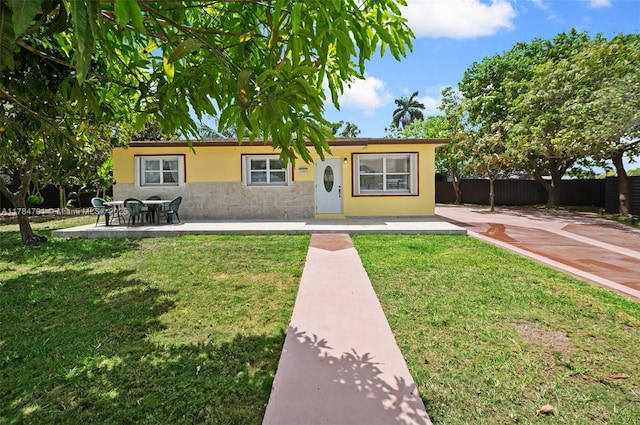 view of front of property featuring stucco siding, a front lawn, fence, and stone siding