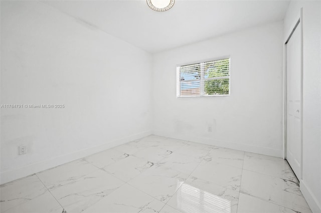 spare room with baseboards and marble finish floor