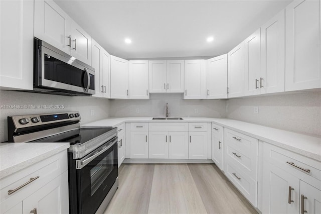 kitchen featuring a sink, light countertops, appliances with stainless steel finishes, and white cabinets