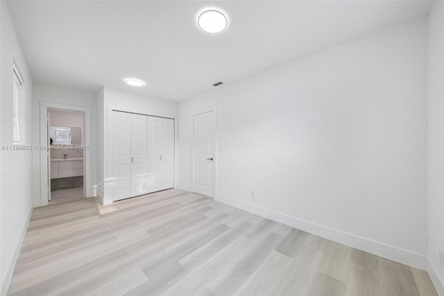 unfurnished bedroom featuring a closet, baseboards, and light wood-style floors