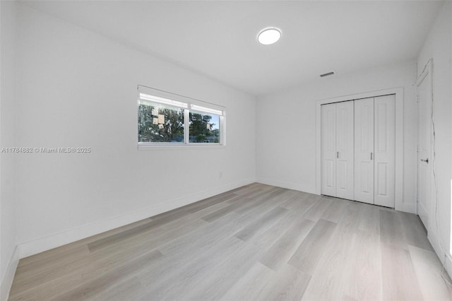 unfurnished bedroom with visible vents, baseboards, light wood-type flooring, and a closet