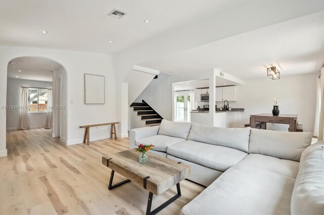 10560 La Placida Dr, Coral Springs, FL 33065 - living room featuring arched walkways, light wood-style floors, stairway, baseboards, and recessed lighting