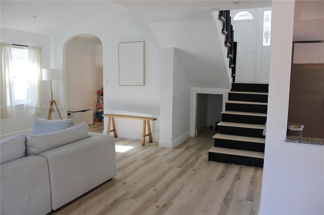 living room with baseboards, stairway, wood finished floors, and arched walkways