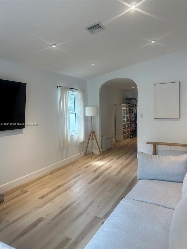 living room with wood finished floors, arched walkways, baseboards, visible vents, and recessed lighting