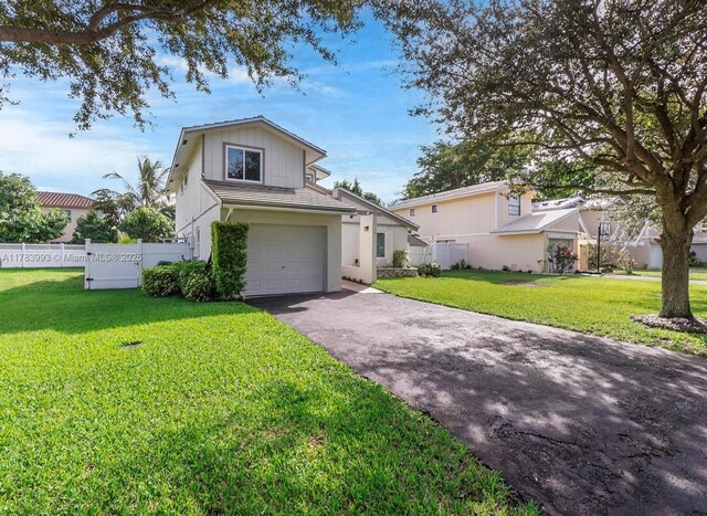 traditional home featuring an attached garage, driveway, fence, and a front lawn