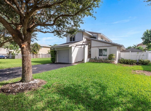 view of front facade with a garage, fence, a front lawn, and driveway