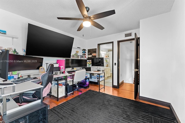 office space featuring a ceiling fan, wood finished floors, and a textured ceiling