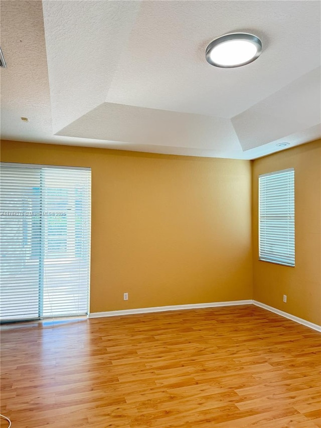 5352 NW 57th Ter, Coral Springs, FL 33067 - empty room featuring light wood finished floors, baseboards, a tray ceiling, and a textured ceiling