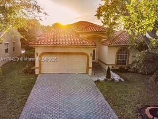 5352 NW 57th Ter, Coral Springs, FL 33067 - mediterranean / spanish house featuring a garage, decorative driveway, a tiled roof, and stucco siding