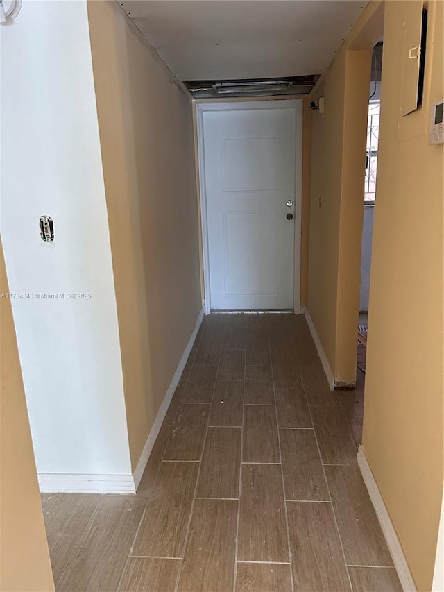 corridor with baseboards and wood finished floors