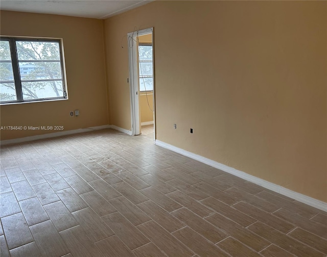 unfurnished room featuring wood tiled floor and baseboards
