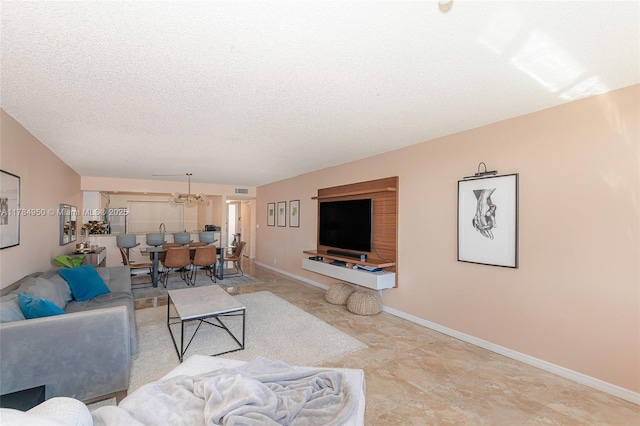 living room featuring baseboards, a textured ceiling, and a chandelier