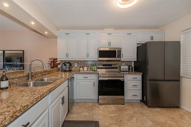 kitchen featuring light stone counters, tasteful backsplash, stainless steel appliances, and a sink