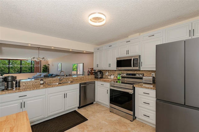kitchen featuring white cabinets, a sink, a textured ceiling, decorative backsplash, and appliances with stainless steel finishes