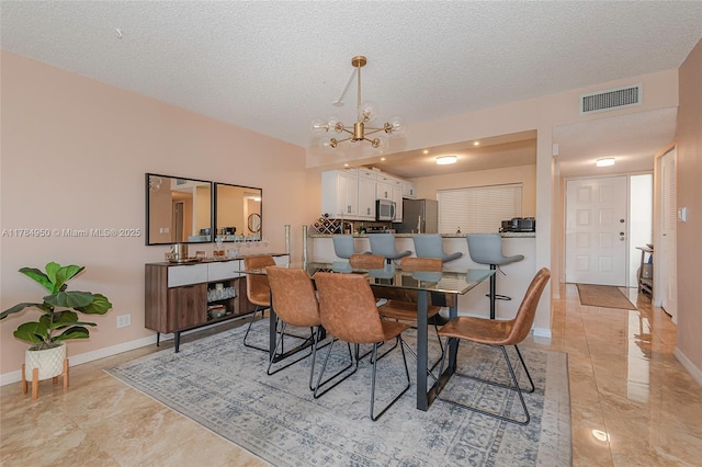dining space featuring a chandelier, a textured ceiling, and baseboards