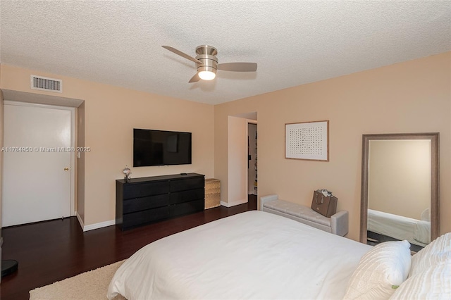bedroom featuring wood finished floors, visible vents, a textured ceiling, and a ceiling fan