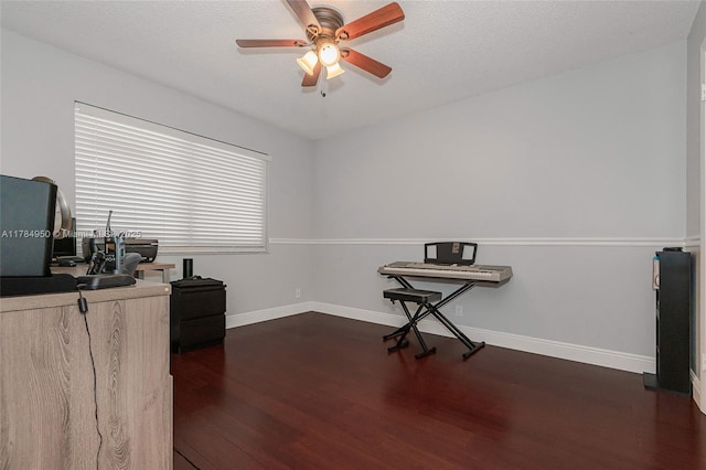 office area with a ceiling fan, baseboards, and dark wood-type flooring