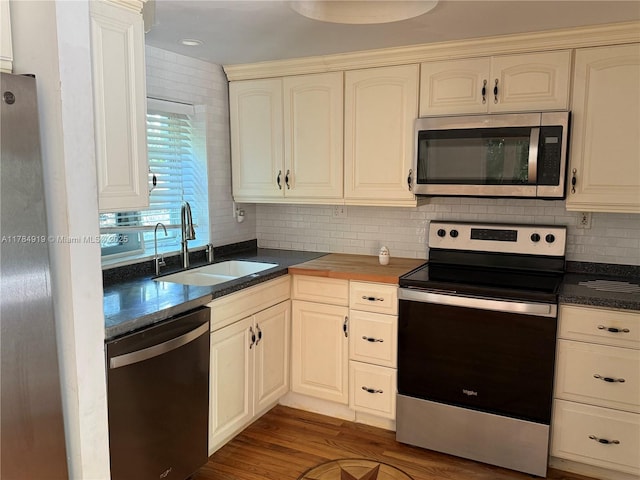 1722 Jefferson Ave, Miami Beach, FL 33139 - kitchen with appliances with stainless steel finishes, wood finished floors, a sink, dark countertops, and decorative backsplash
