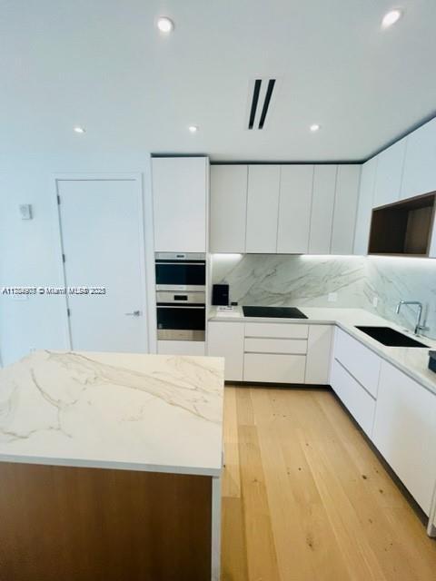 304 Ocean Dr Unit 302, Miami Beach, FL 33139 - kitchen featuring a sink, modern cabinets, stainless steel double oven, white cabinetry, and recessed lighting