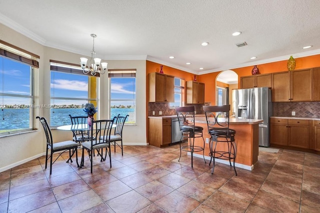 16519 SW 54th Ct, Miramar, FL 33027 - kitchen with stainless steel appliances, a chandelier, brown cabinetry, a kitchen bar, and recessed lighting